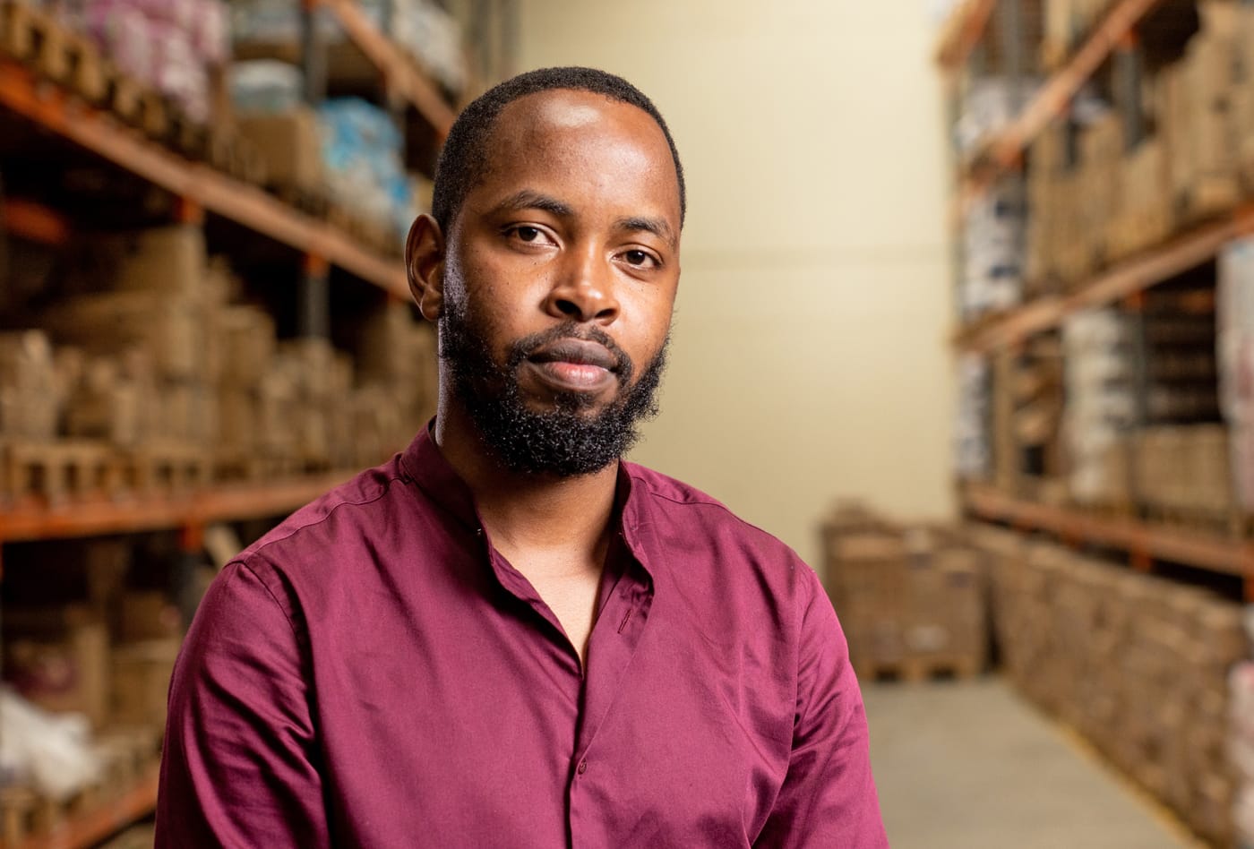 Man in a burgundy shirt standing in a warehouse