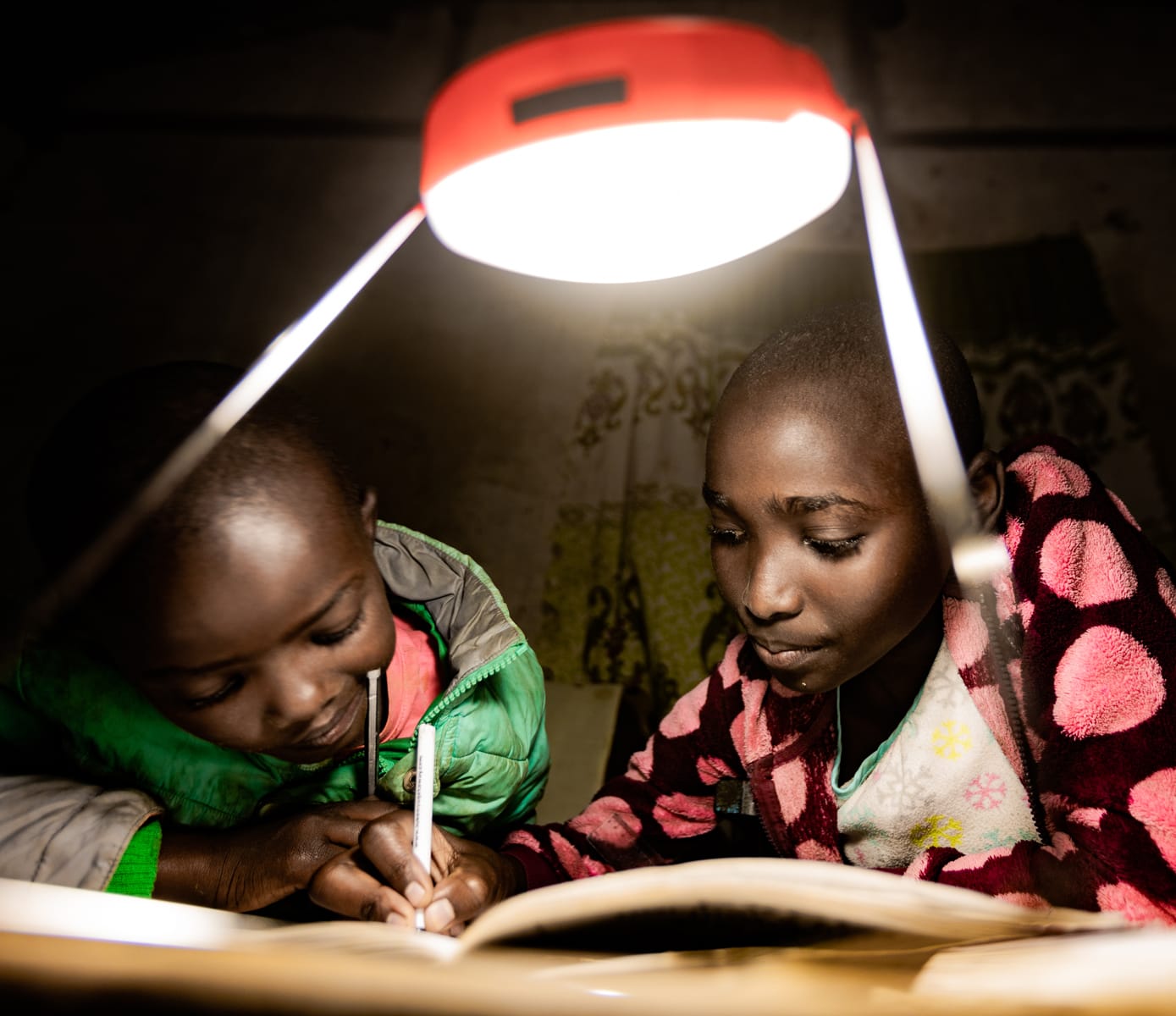 Two kids studying under an electric light